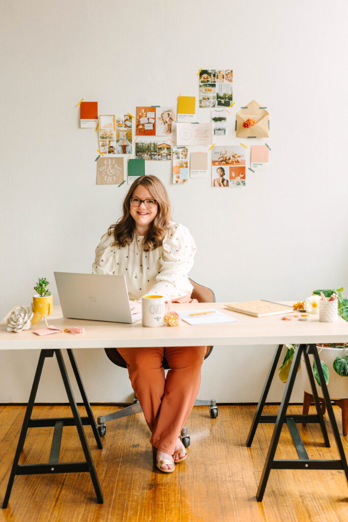 Des Moines Iowa woman brand owner sitting at desk with a computer smiling for headshot